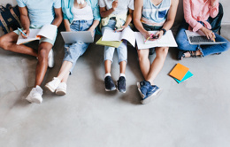 overhead portrait young people with laptops smartphones sitting together floor students writing lectures holding textbooks their knees